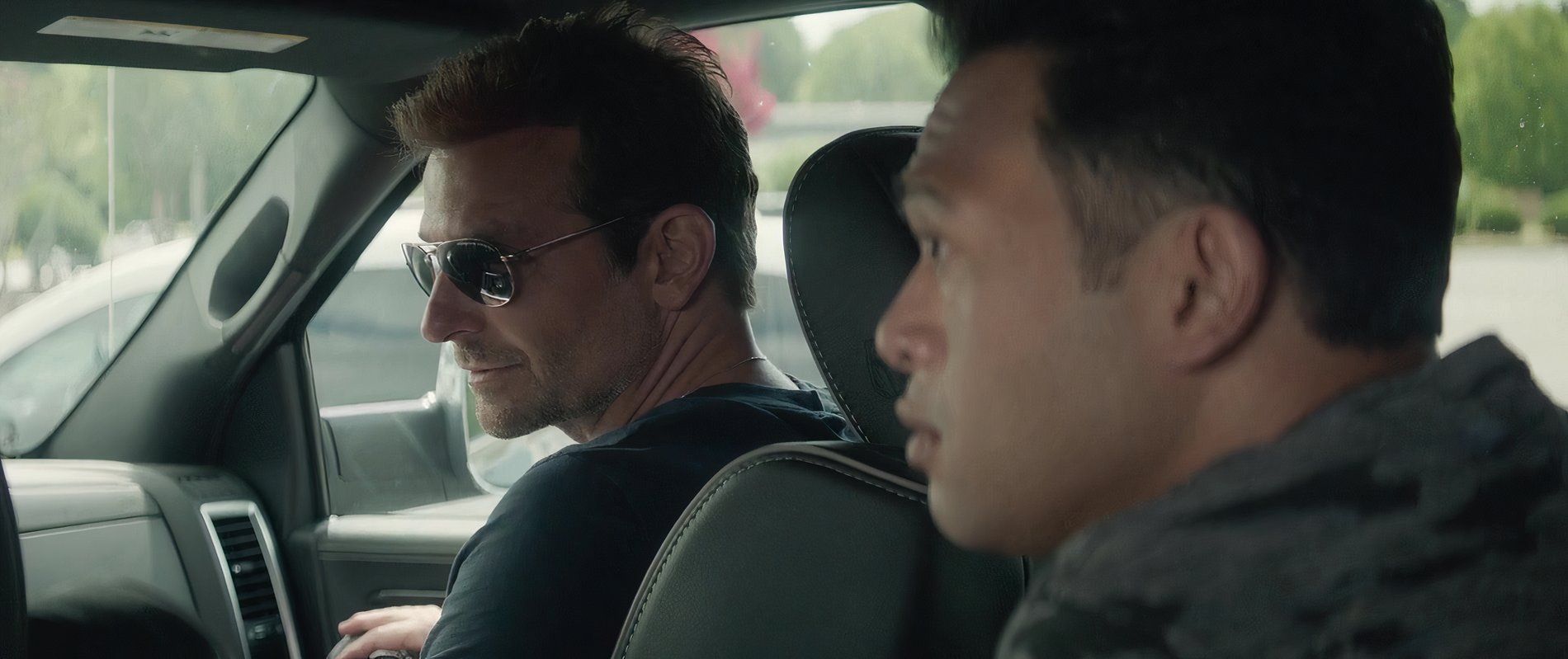 Bradley Cooper as D E A Officer Colin Bates sitting a car with a fellow officer in The Mule 