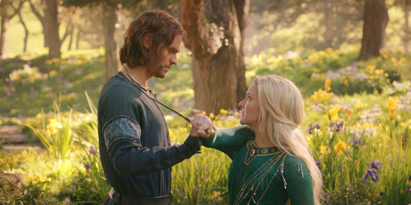 A profile view of Sauron as Halbrand (Charlie Vickers) grabbing Galadriel's (Morfydd Clark) arm as she tries to stab him with her dagger as they stand in an elvish garden filled with yellow flowers in The Rings of Power