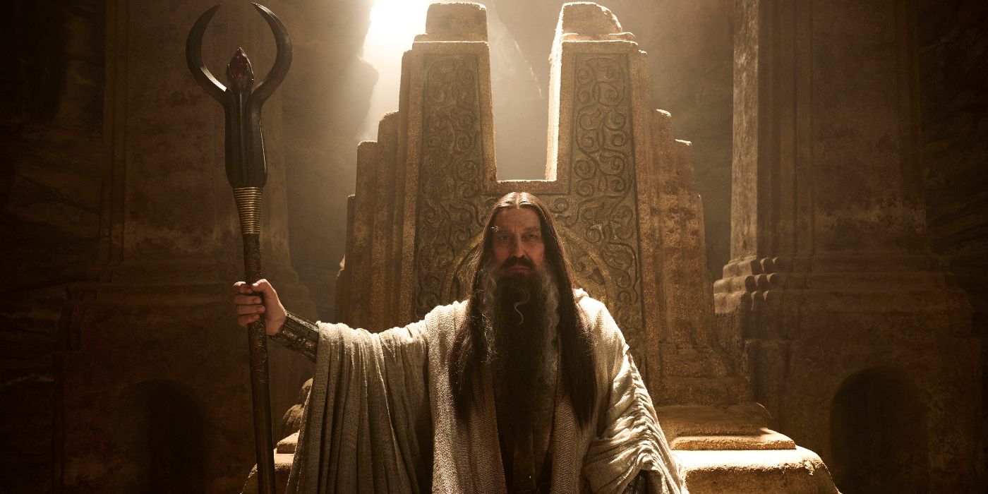 Ciaran Hinds as the Dark Wizard sitting on a throne with a large staff in Rings of Power Season 2