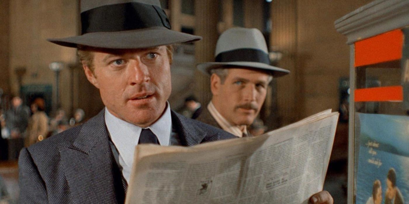 Johnny Hooker (Robert Redford) pretends to read a newspaper as he spies around a train station while Henry Gondorff (Paul Newman) peers at him from behind in 'The Sting' (1973).