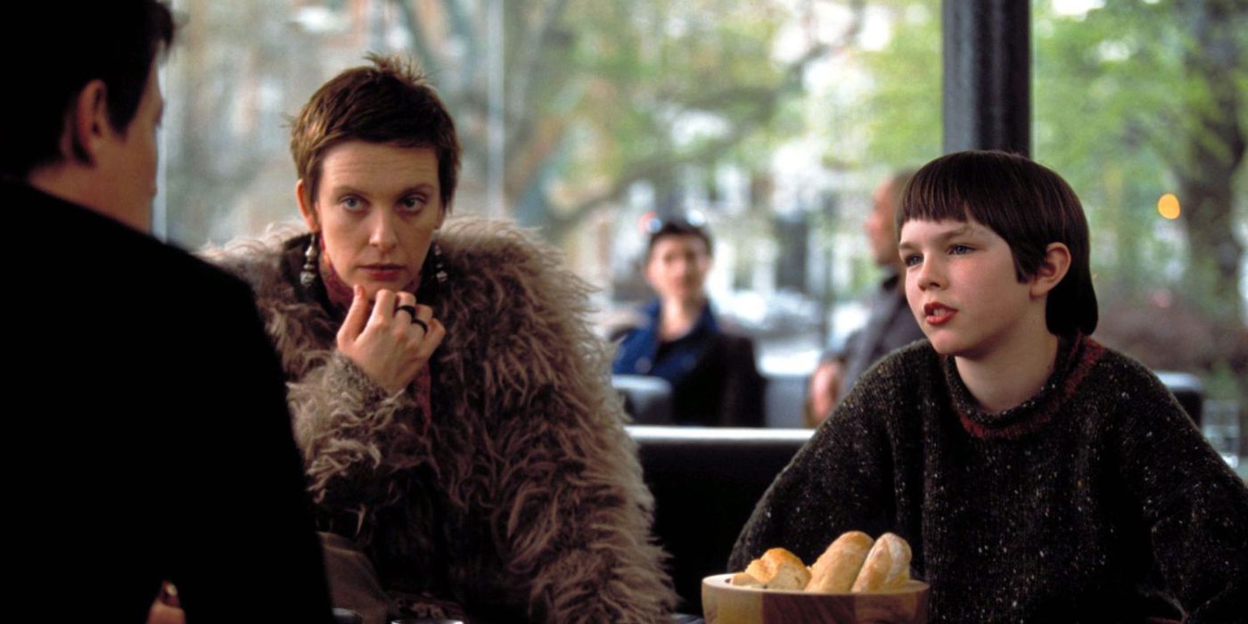 Toni Collette as Fiona & Nicholas Hoult as Marcus in a restaurant talking to someone off-screen in About A Boy