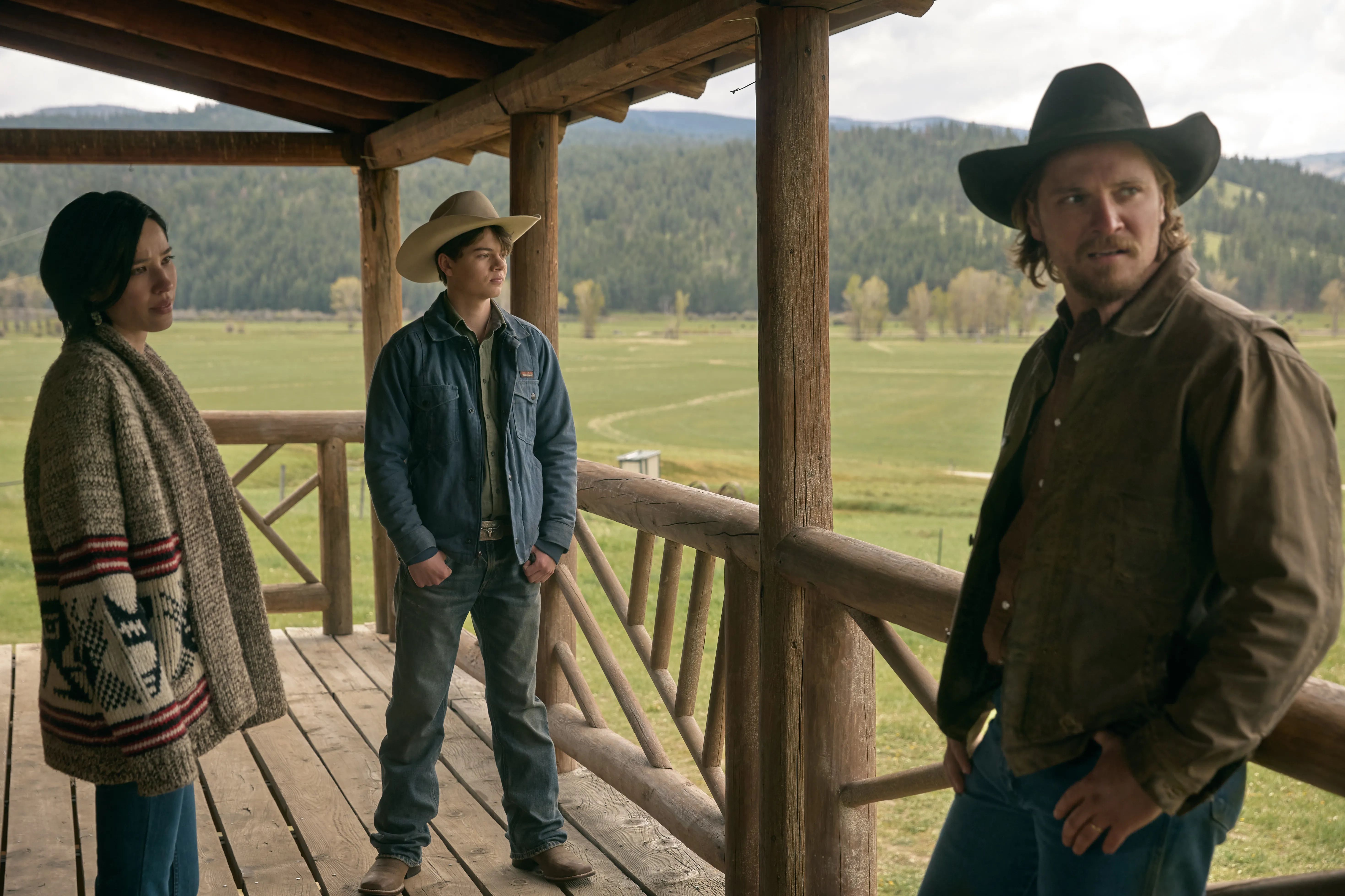 Kelsey Asbille, Brecken Merril, and Luke Grimes standing on a porch in Yellowstone Season 5