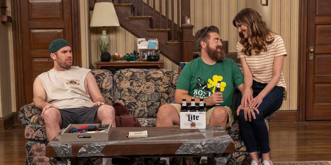 Erinn Hayes sits on the arm of a couch looking at someone in Kevin Can F**k Himself