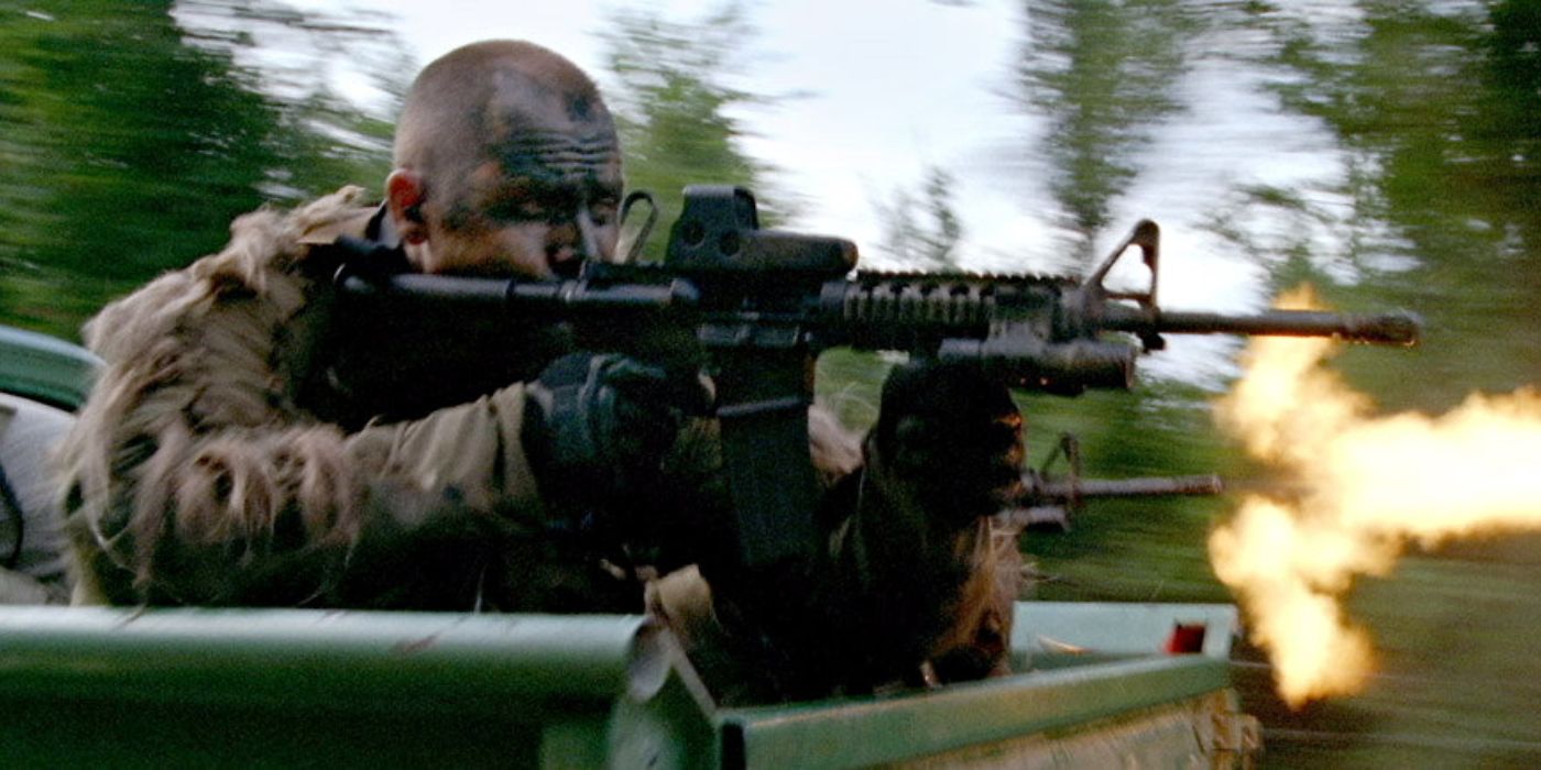 A soldier firing a gun while he is on the bed of a truck