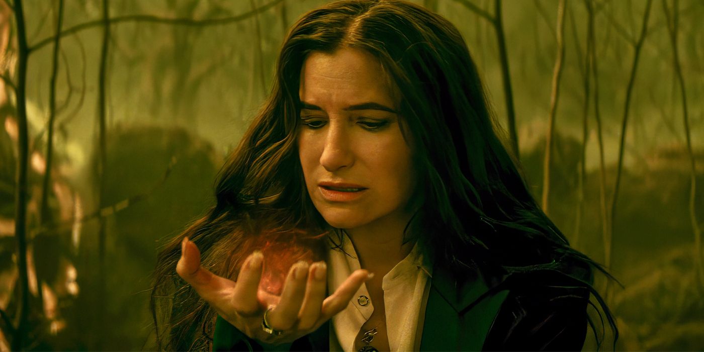 Kathryn Hahn raising up her palm and looking down at the orange magic in it