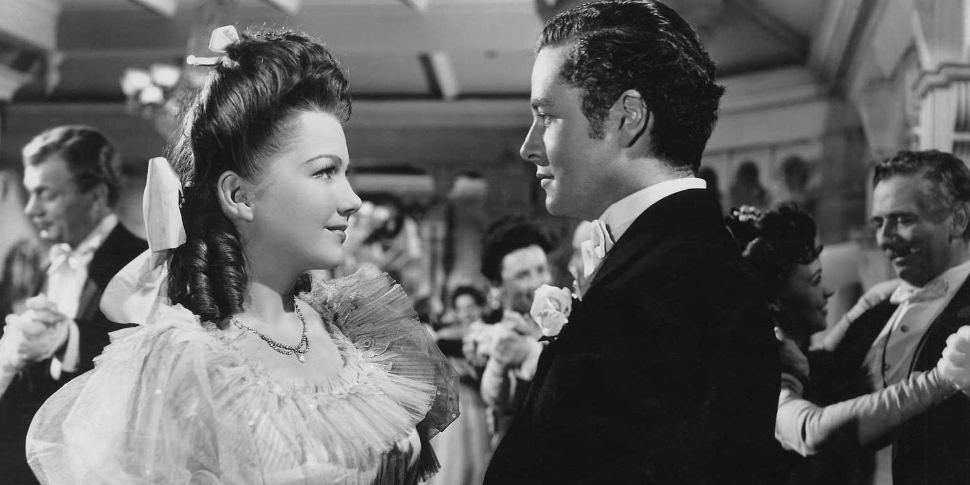 Anne Baxter standing in front of Tim Holt at a gathering in The Magnificent Ambersons (1942)