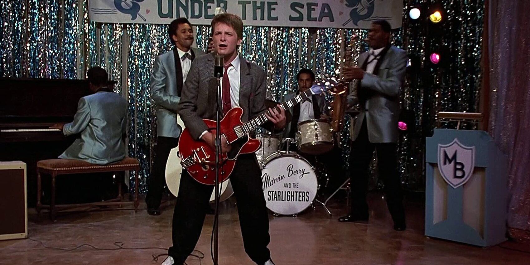 Marty Mcfly singing Johnny B Goode while playing a bright red guitar on stage at the Under the Sea dance in 'Back to the Future' (1985)