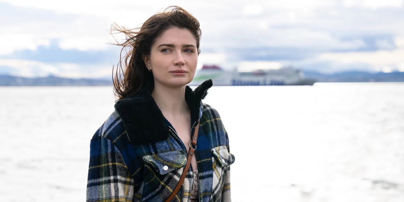 Becka Garvey (Eve Hewson) stands in front of the ocean in a plaid coat, with her hair blowing in the wind in a scene from 'Bad Sisters.'