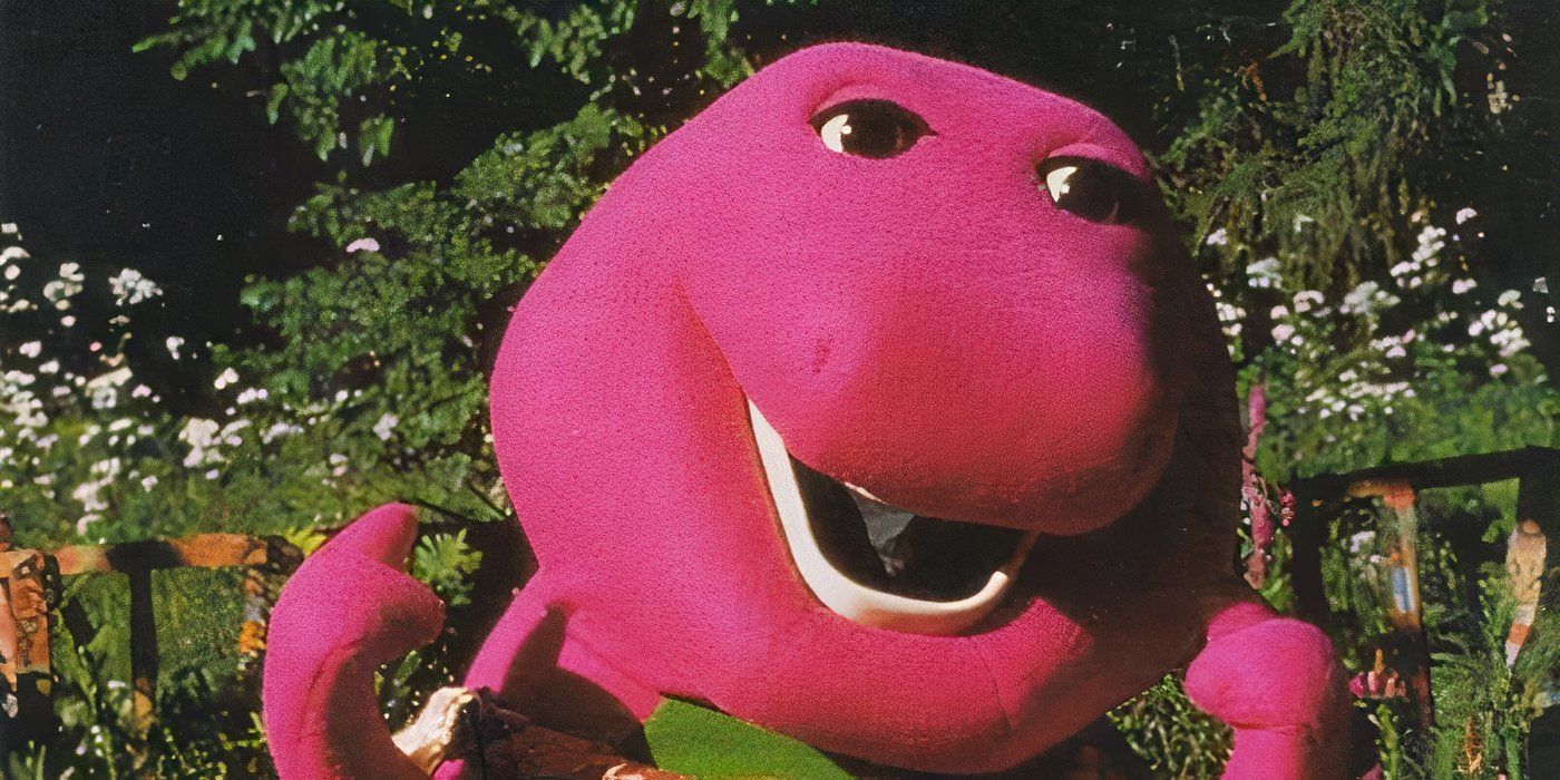 The character Barney stands outside in front of flowers in Barney's Great Adventure.