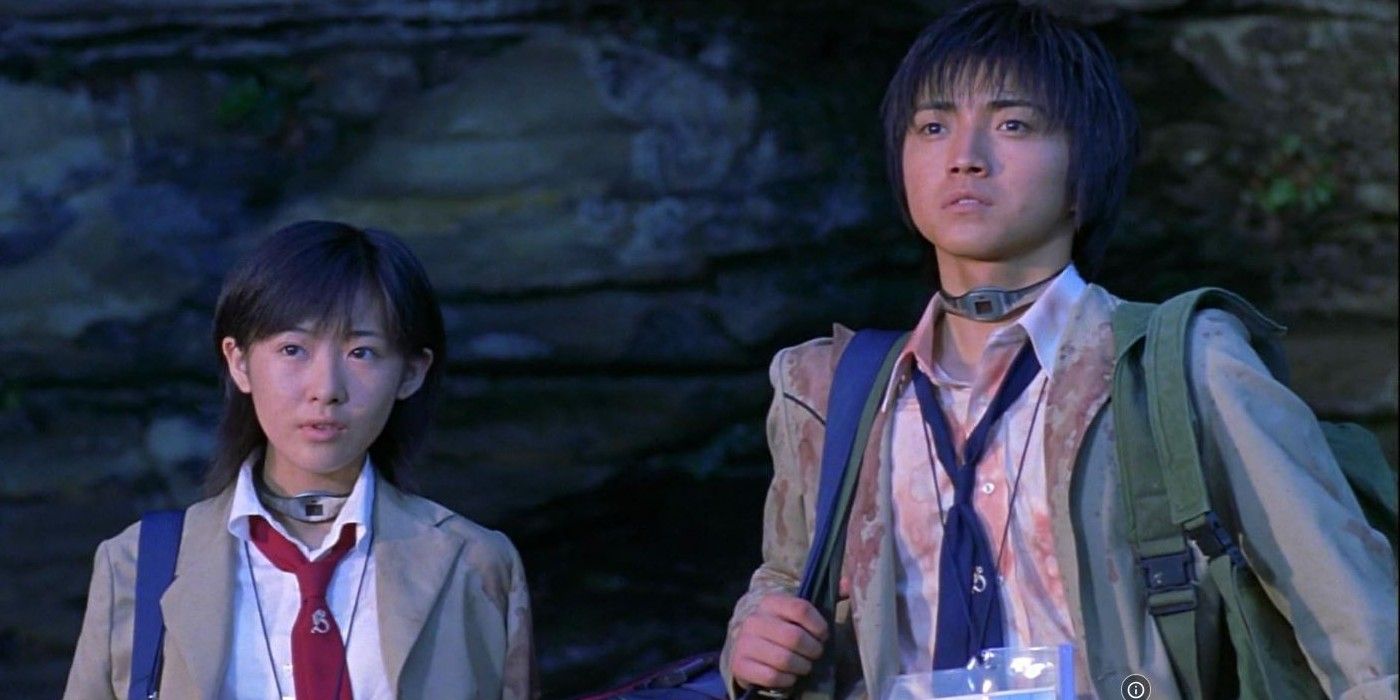 Aki Maeda and Tatsuya Fujiwara as Noriko and Shuya wearing bloodstained school uniforms and collars around their necks in Battle Royale (2000)