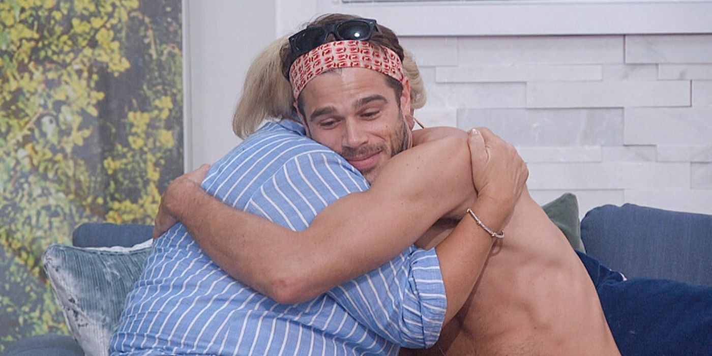 Tucker from Big Brother with no shirt wearing a red bandana and hugging Angela.
