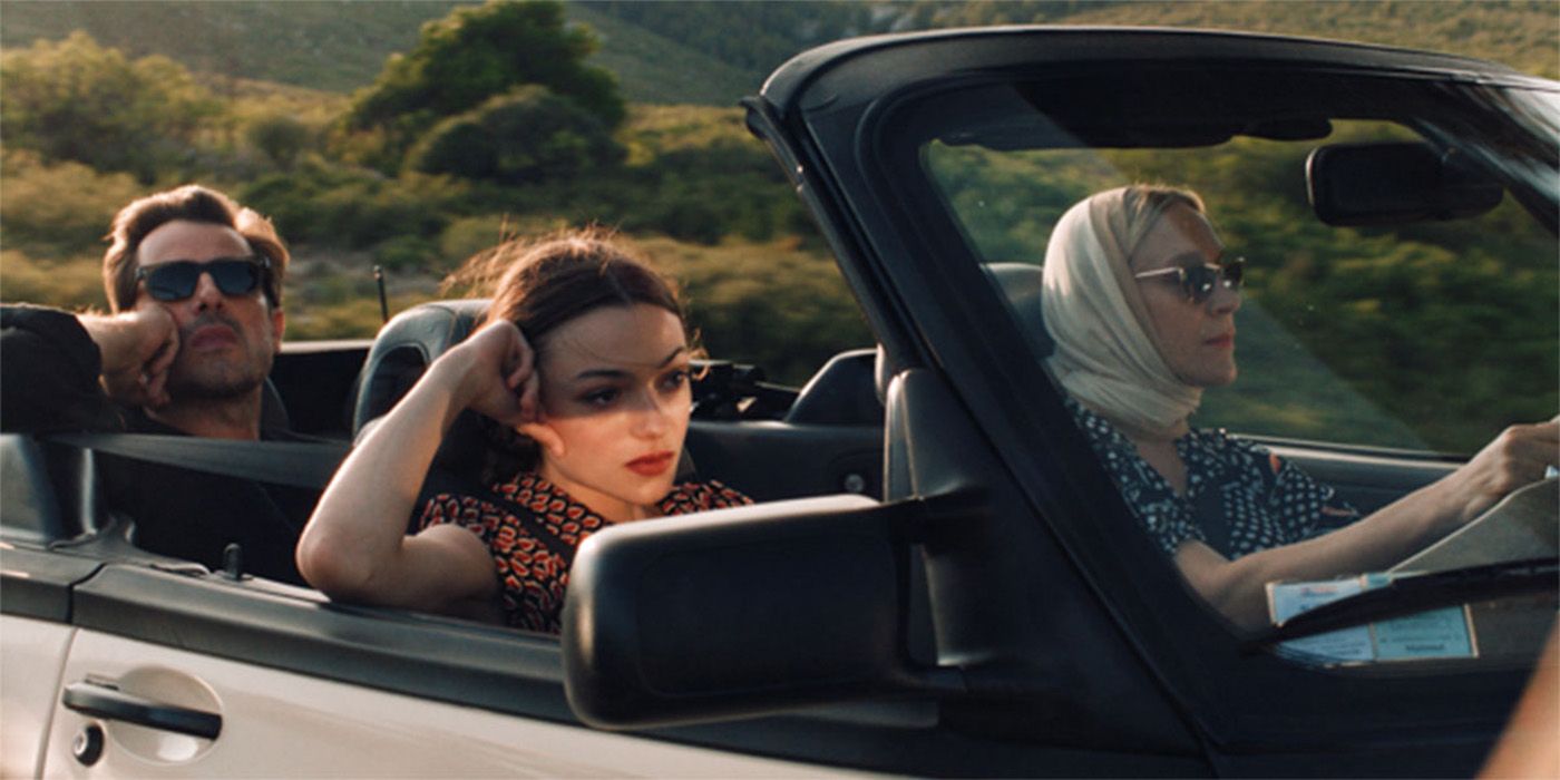 Chloe Sevigny, Lily McInerny and Claes Bang in an open-top convertible driving with trees in the background