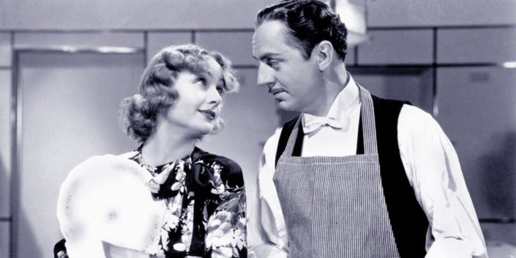 Carole Lombard and William Powell standing next to each and looking at each other in My Man Godfrey (1936)