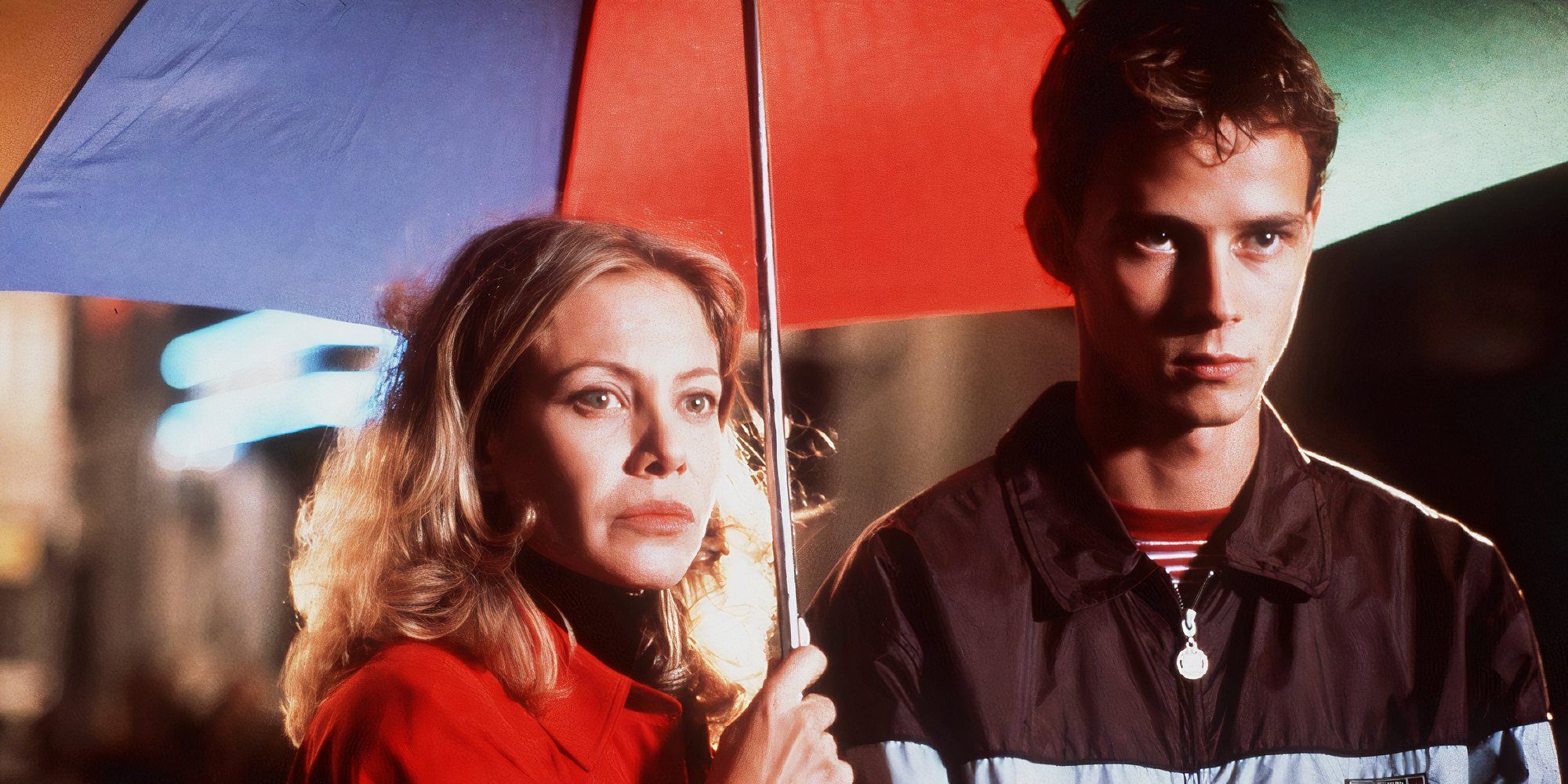 Cecilia Roth and Eloy Azorín in All About My Mother standing under an umbrella