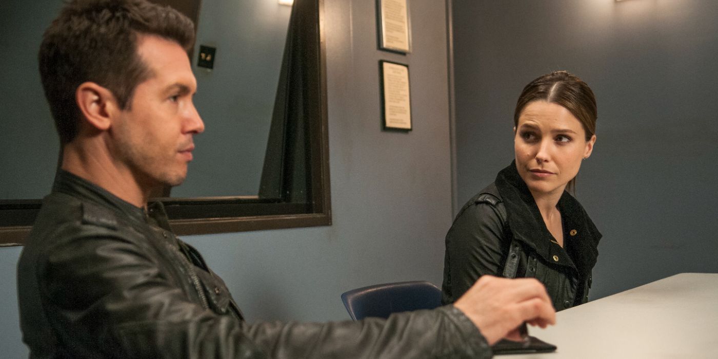 A man and woman sit at a table in a police interrogation room in Chicago P.D.