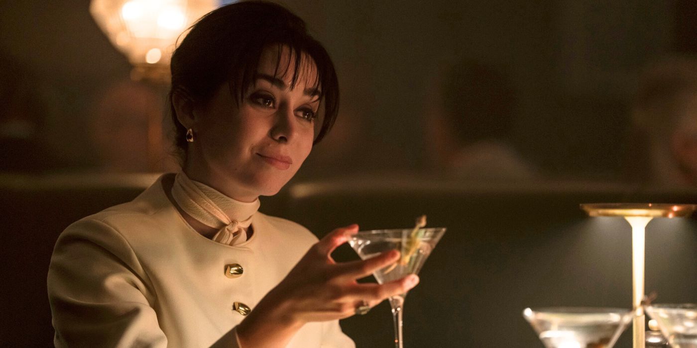 Cristin Milioti as Sofia Falcone in a white dress-suit, holding up a martini glass in The Penguin.