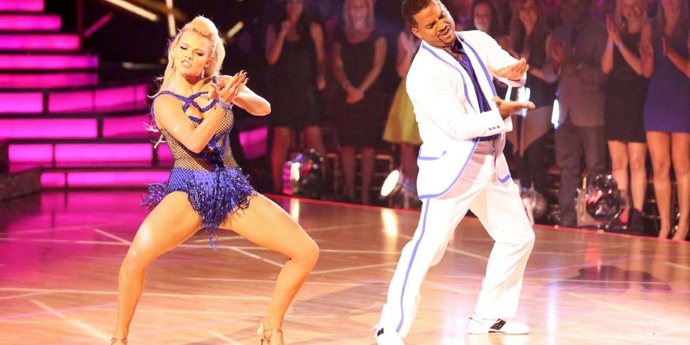 Alfonso Ribeiro viste un traje blanco y morado mientras baila con su pareja de baile en Dancing with the Stars.