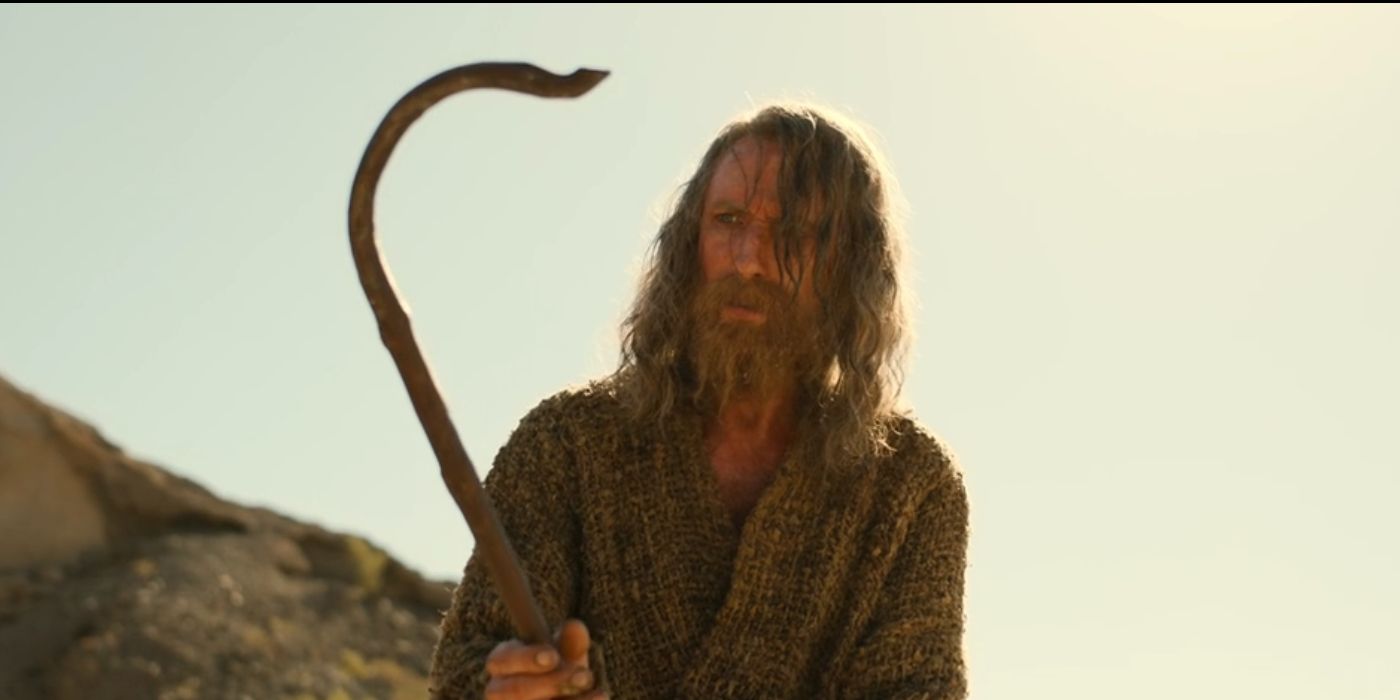 Daniel Weyman as the Stranger holds a staff in the desert in 'The Rings of Power' Season 2, Episode 2. 