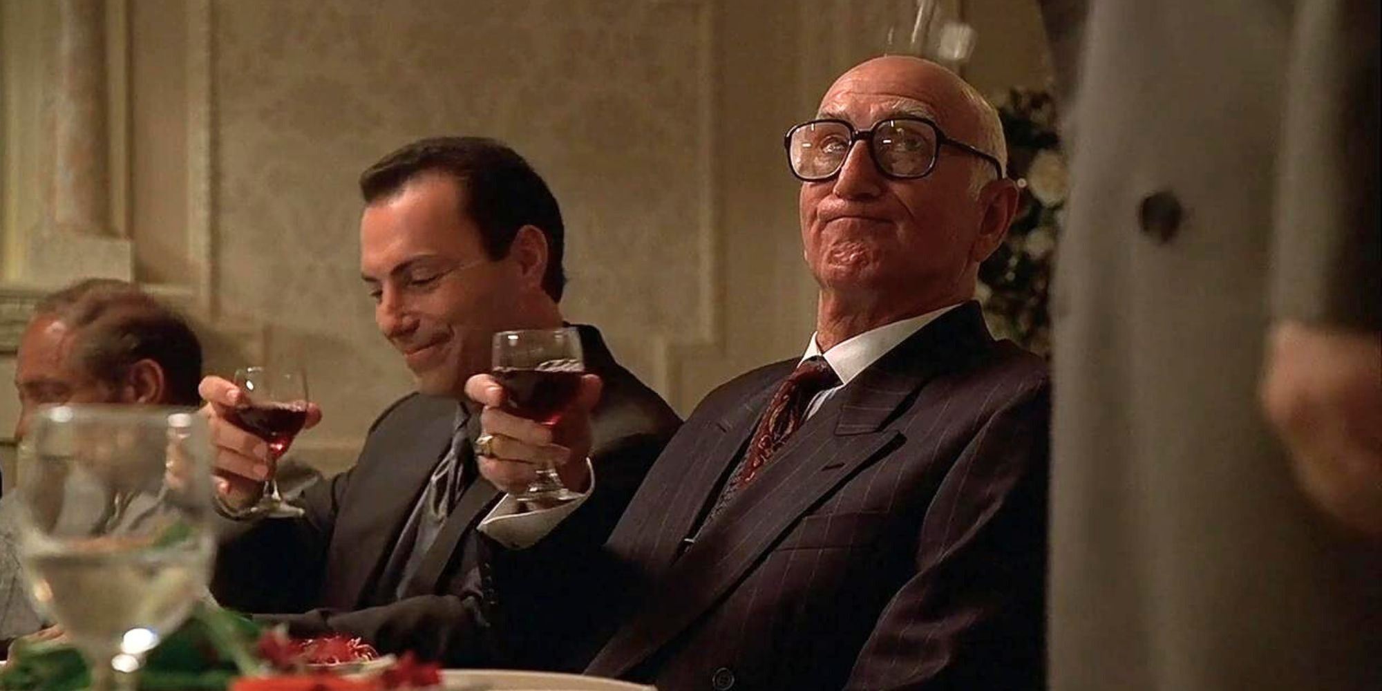 Dominic Chianese sitting at a table with wine with Al Sapienza sitting next to him in The Sopranos.