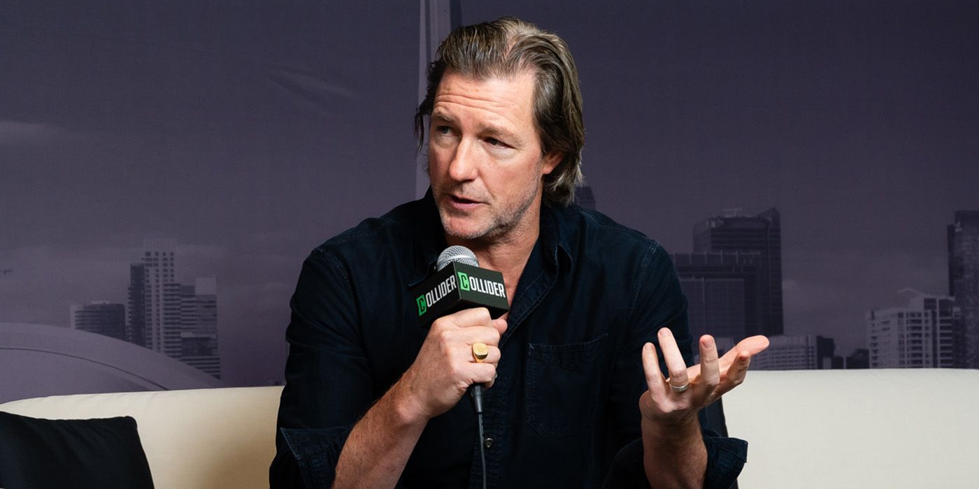 Edward Burns holding a microphone in the Collider studio at TIFF