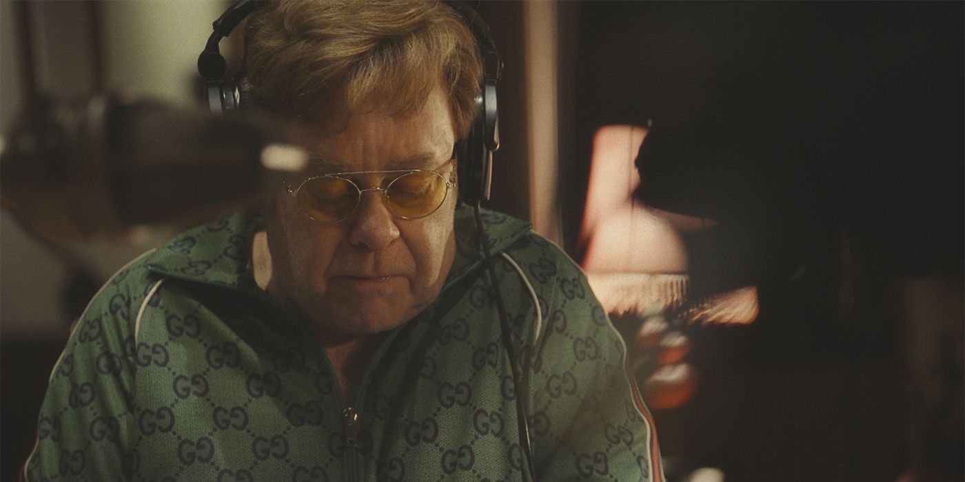 Elton John looking down with headphones on