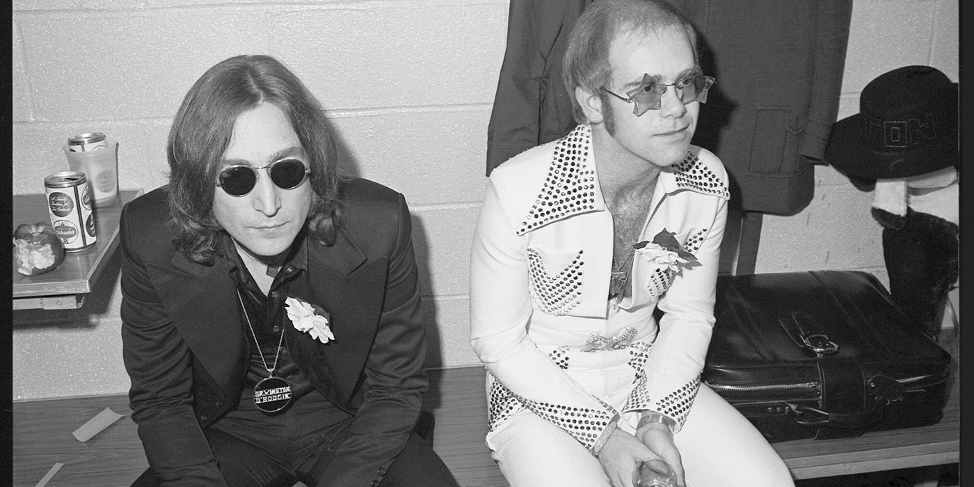 Black and white photo of John Lennon and Elton John sitting together backstage