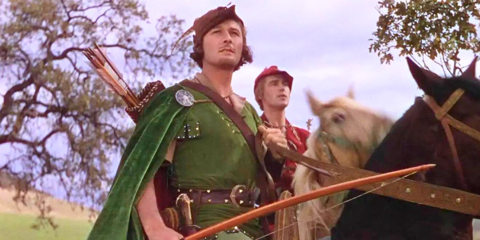 Robin Hood, played by actor Erroll Flynn, and Will Scarlet, played by actor Patric Knowles, both on horseback in The Adventures of Robin Hood.