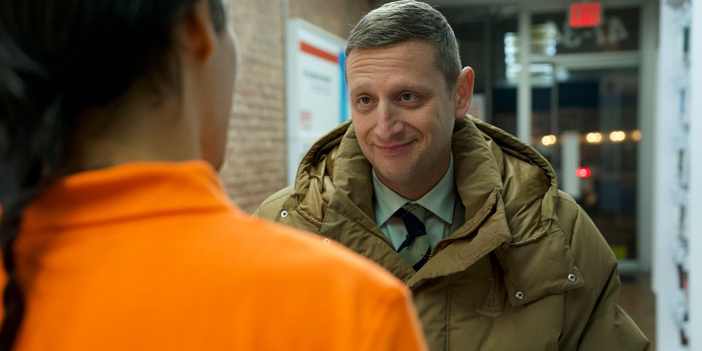 Tim Robinson smirking at someone in an orange shirt 