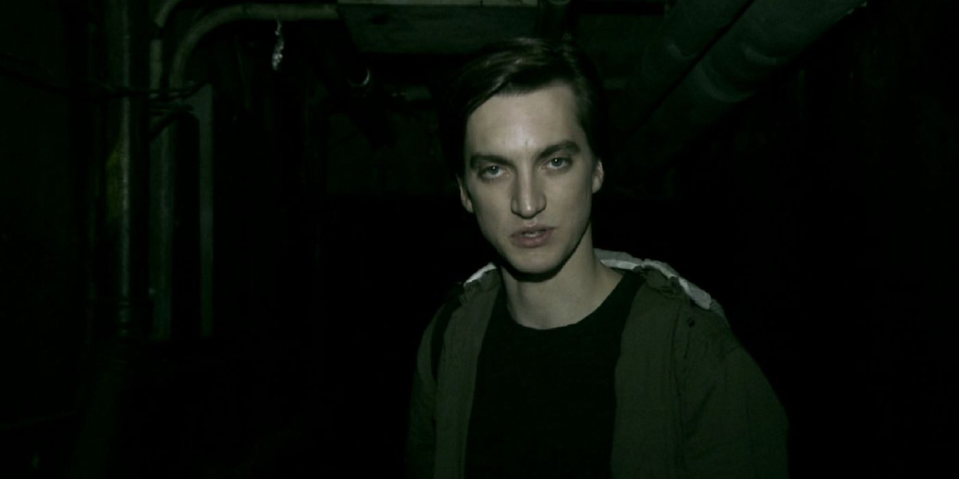 A white man in his 20s standing in a dark alleyway looking at the camera in Grave Encounters 2
