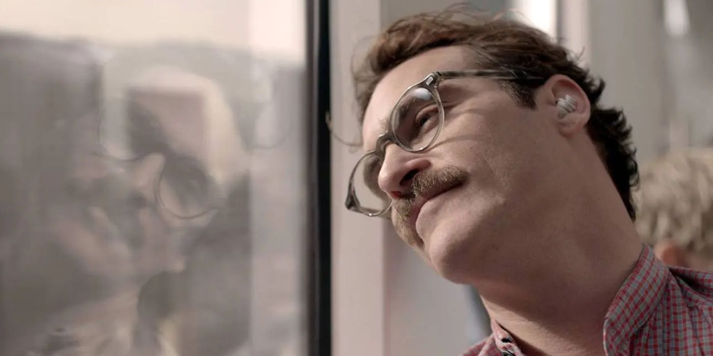 Theodore Twombly (Joaquin Phoenix) leans his head against a window, looking out and smiling in Her (2013).