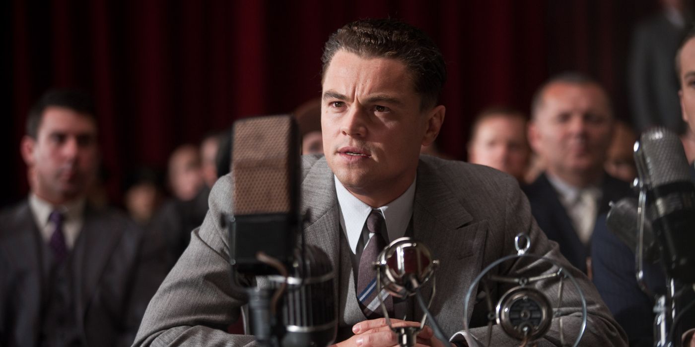 J. Edgar Hoover (Leonardo DiCaprio) sits in court behind a swarm of microphones with a large crowd behind him in 'J. Edgar' (2011).