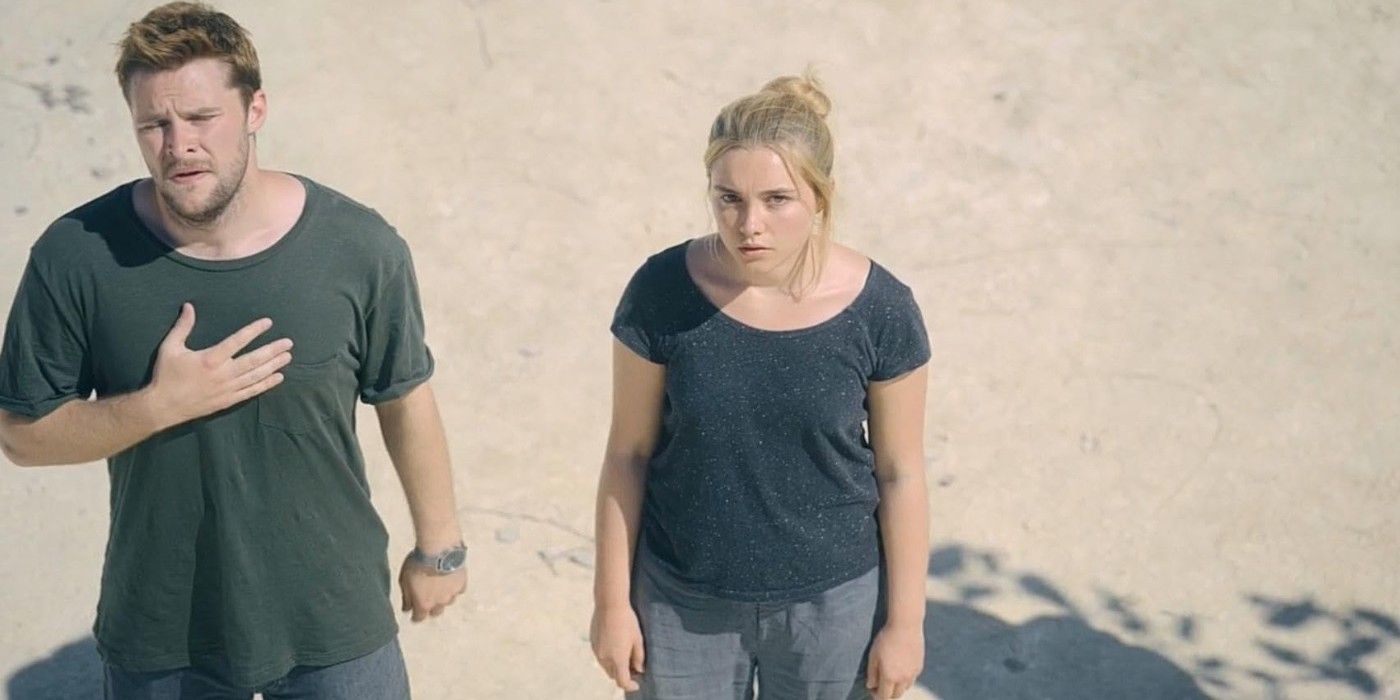 Jack Reynor and Florence Pugh gazing upward as they stand in a dirt clearing in &ldquo;Midsommar&rdquo;