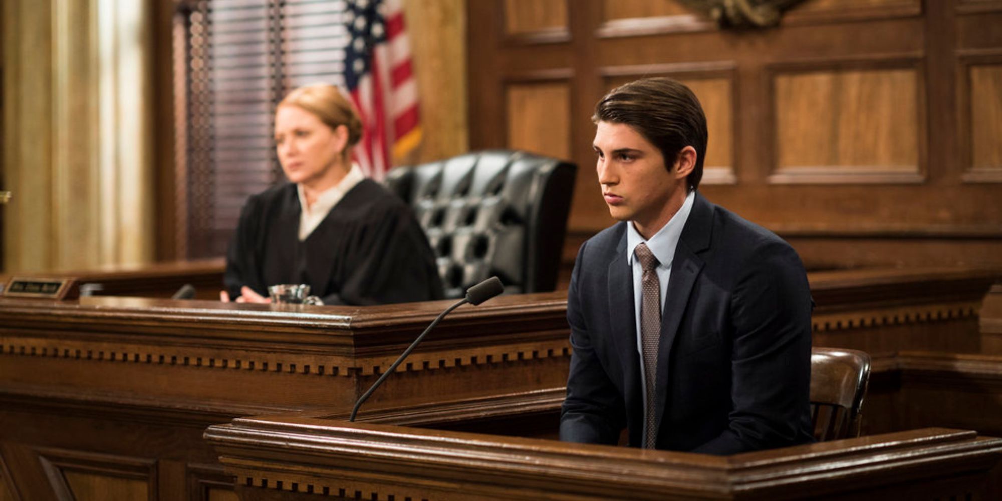 Jenna Stern sitting in the judge's chair next to Gage Banister who is seated on the witness stand in a court room in Law & Order SVU