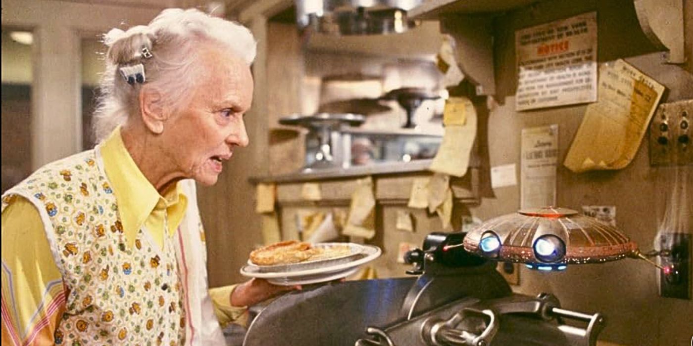 Jessica Tandy holds a pie while looking at a small flying saucer from the movie Batteries Not Included.