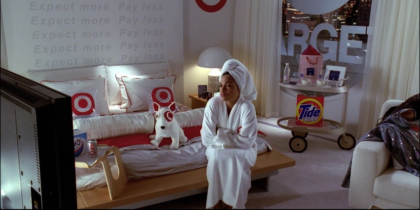 Rosario Dawson as Val in 'Josie and the Pussycats' sitting in a room with Target pillows, a can of Coke, a box of Tide, and more product placement