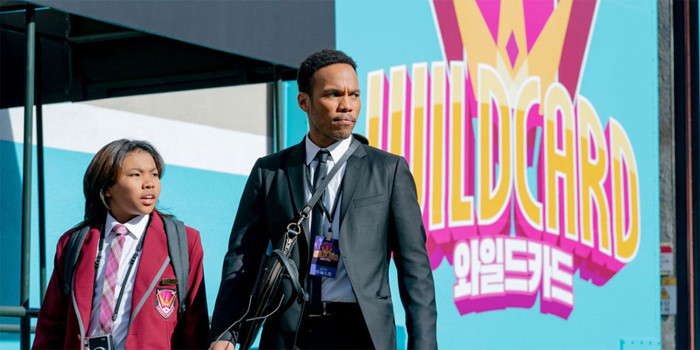 A man and a young boy walking down the street looking off to their side