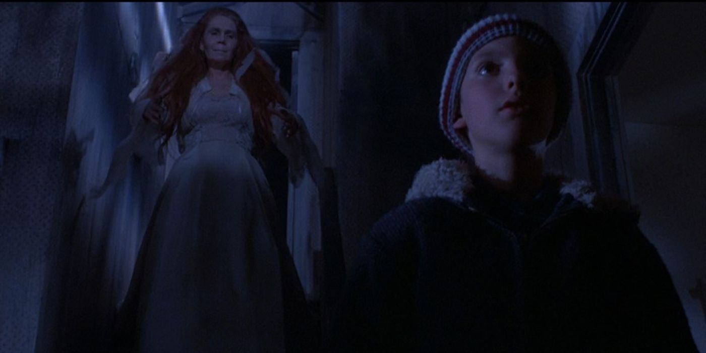 a ghostly woman in a white gown stands behind a little boy wearing a winter hat and jacket