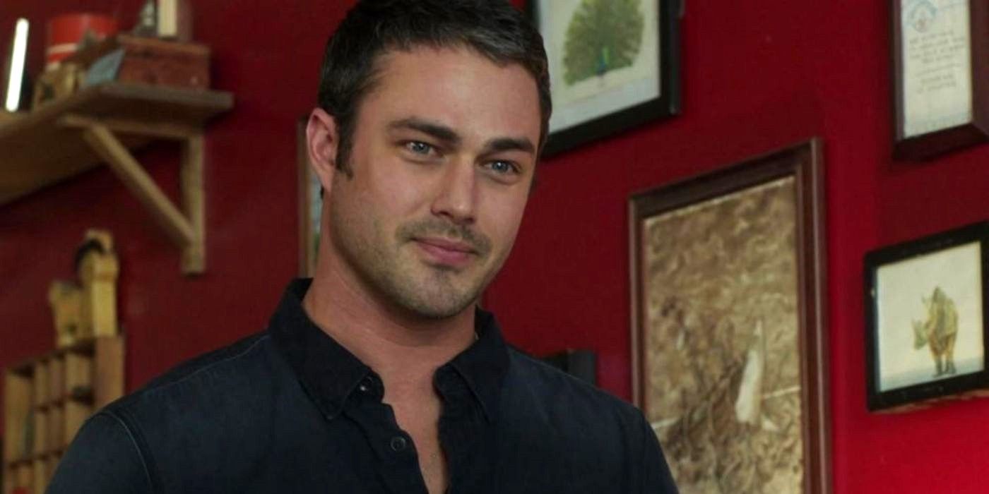 Taylor Kinney as Kelly Severide in a room with red wallpaper and artwork in frames in Chicago Fire.