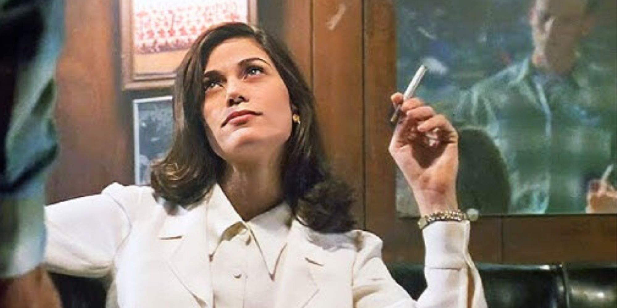 Linda Fiorentino sitting down at a table with a cigarette in her hand looking up at someone standing in front of her in The Last Seduction (1994)