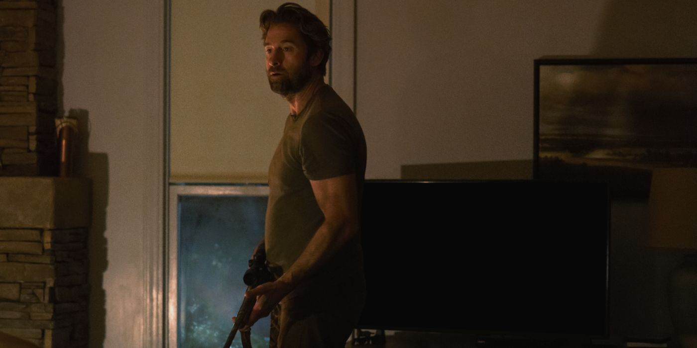 Scott Speedman wears a dark green tee and holds a gun