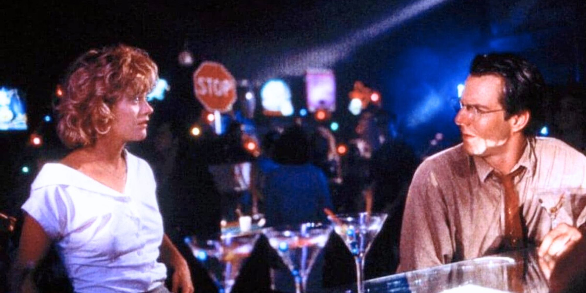 Meg Ryan standing in front of Dennis Quaid who is sitting at a bar in D.O.A. (1988)