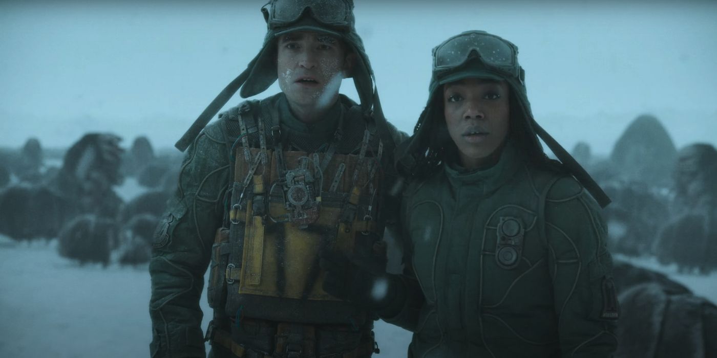 Robert Pattinson and Naomi Ackie wearing winter gear while standing next to each other on a wintery planet in Mickey 17.