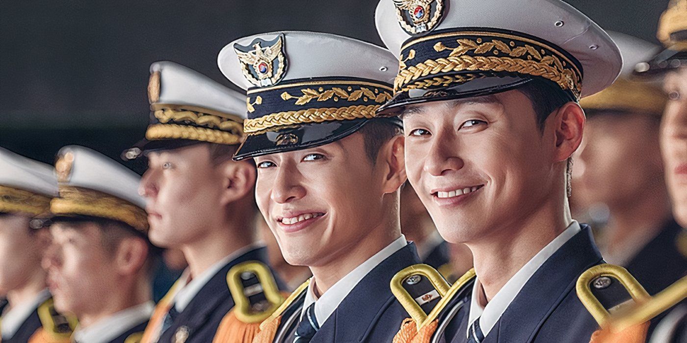 A group of police academy graduates are standing in a line, and the two main characters are looking at the screen and smiling widely