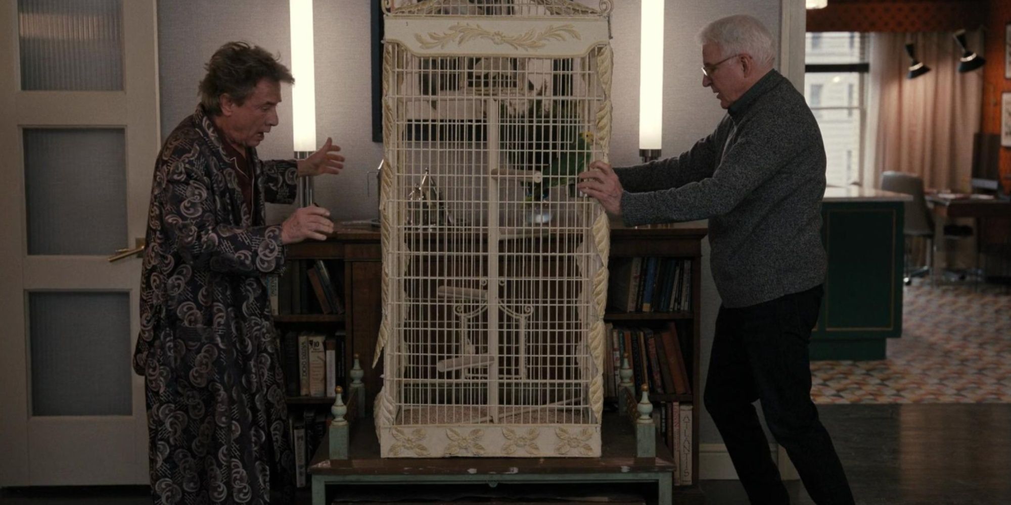 Oliver and Charles standing on either side of a bird cage in Only Murders in the Building
