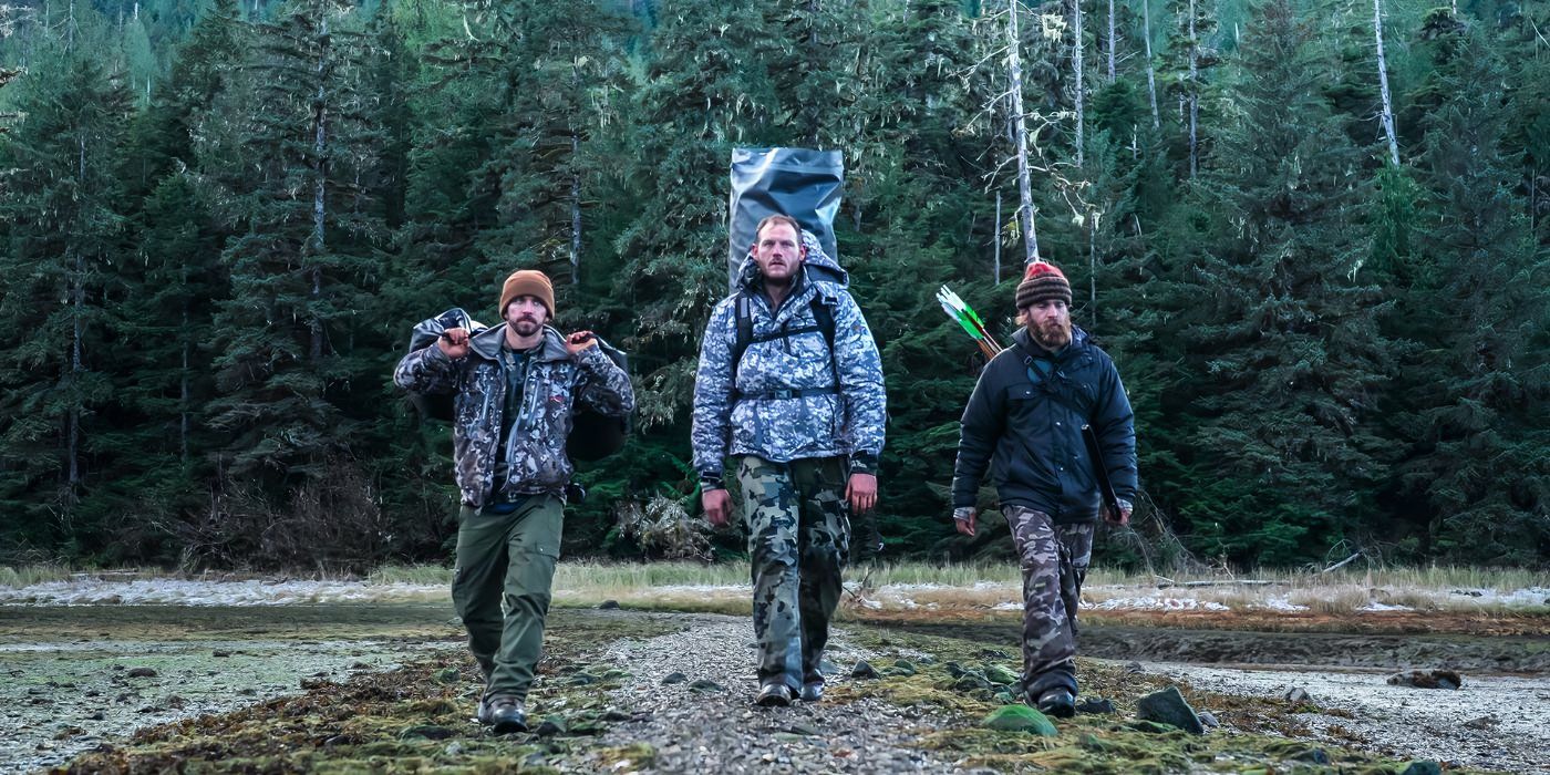three men wearing camo walk through the alaskan wilderness