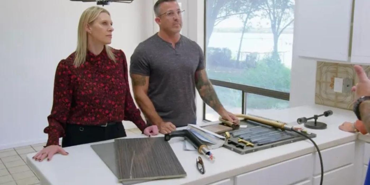 A couple stand in a kitchen being renovated and look stressed in Renovation Impossible.