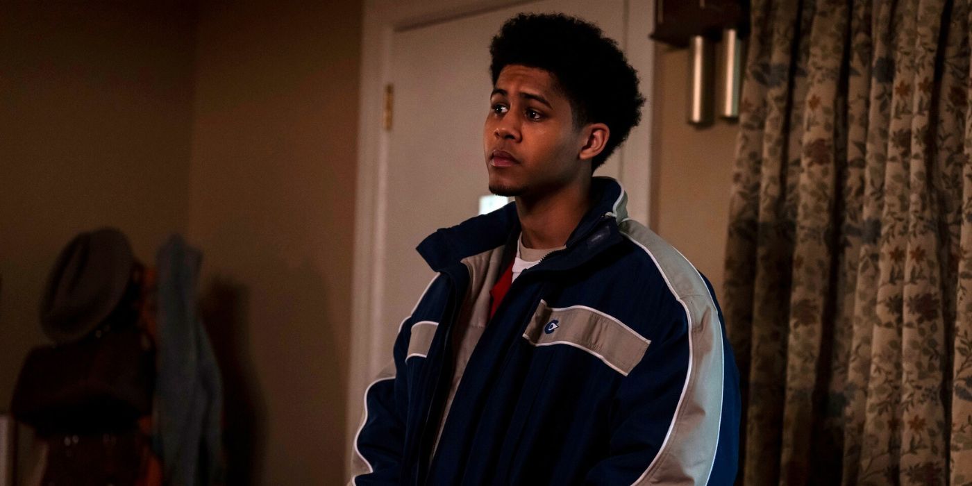 Rhenzy Feliz as Victor Aguilar standing by the front door wearing a navy blue and gray jacket in The Penguin.