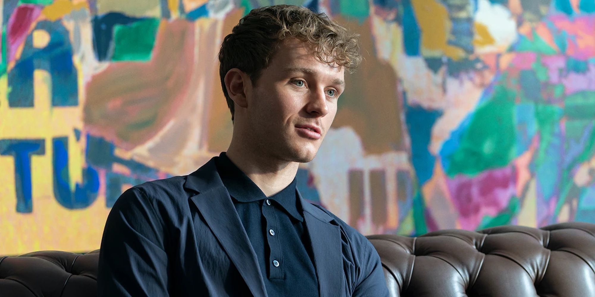 Robert Spearing (Harry Lawtey) sitting in front of a colorful background in Industry Season 3.