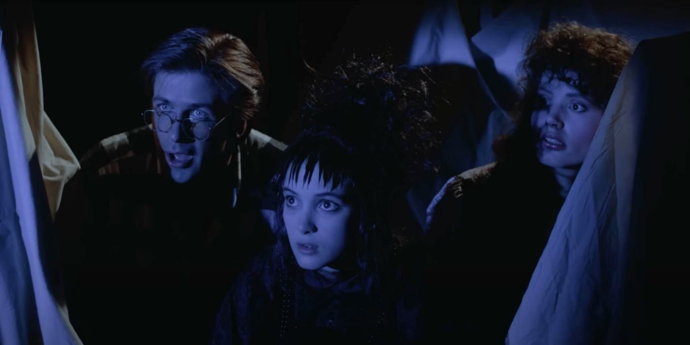 Adam (Alec Baldwin), Lydia (Winona Ryder), and Barbara (Geena Davis) hide from Lydia's parents in Beetlejuice (1988).