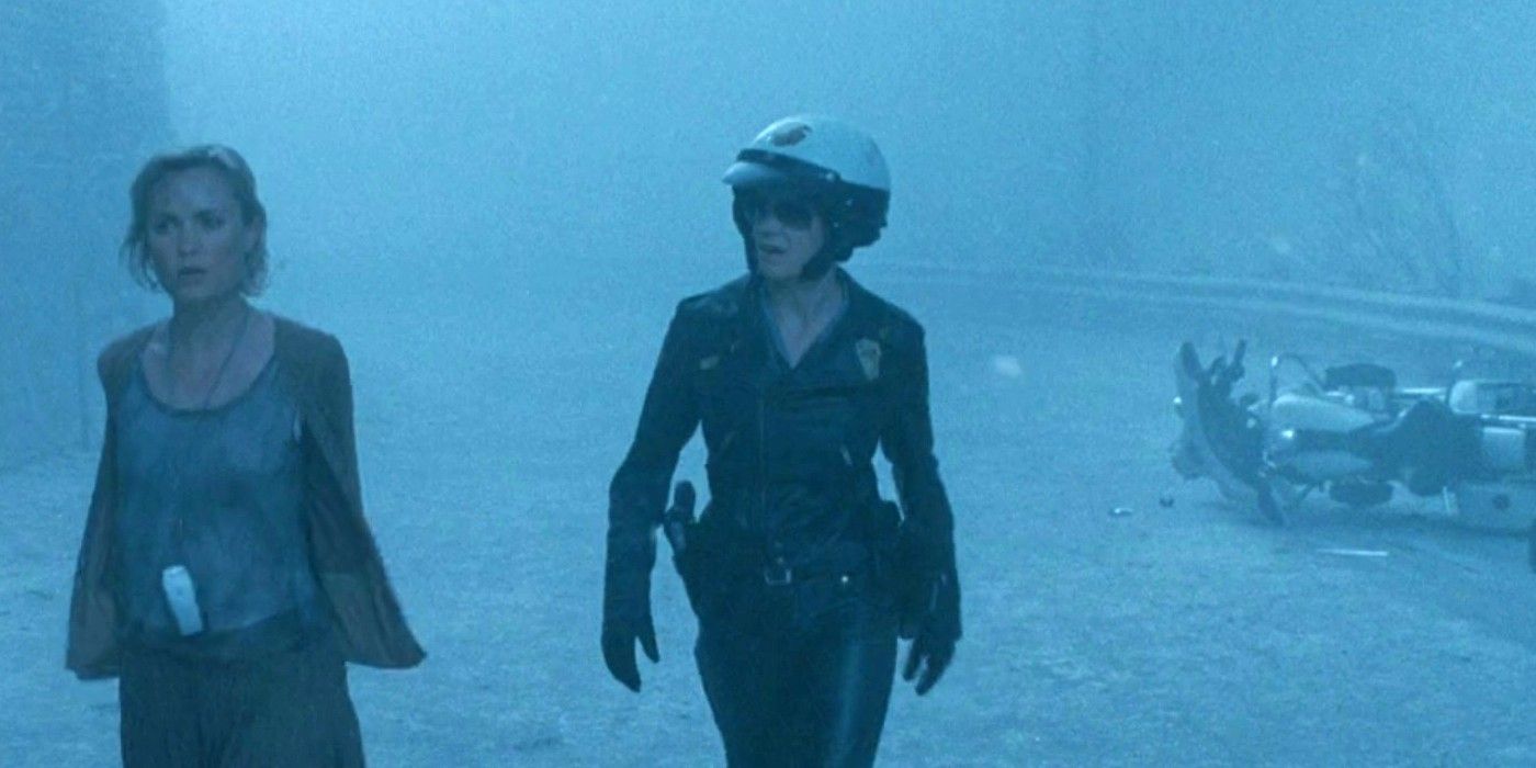 Radha Mitchell and Laurie Holden as Rose and Cybil walking down a foggy road with a crashed police bike behind them in Silent Hill (2006)